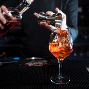 Bartender beim Drink mixen vor dunklem Hitnergrund